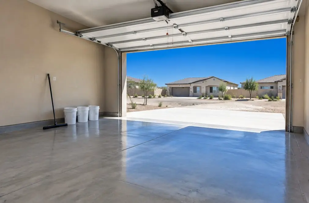 Illustration: a bare ground-concrete garage floor in a Central Valley tract home with three plain pails of coating and a squeegee set along one wall